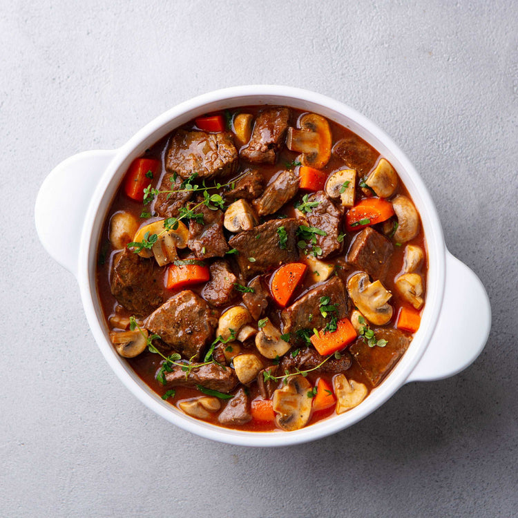 Beef bourguignon stew with vegetables. Grey background. Top view.