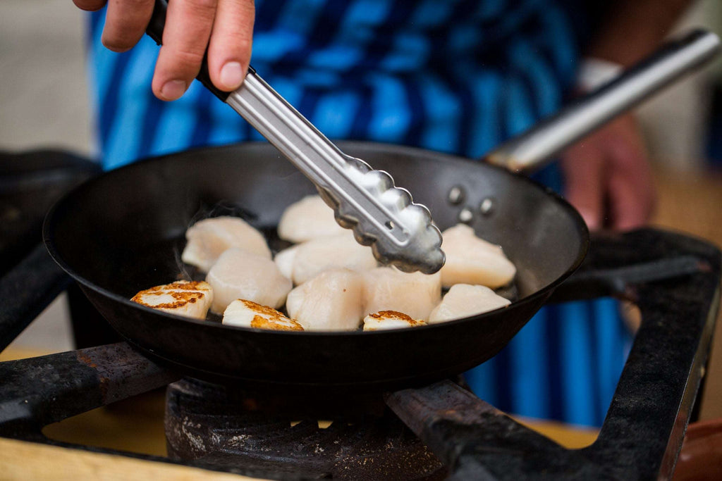 close up of scallops frying in cast iron pan