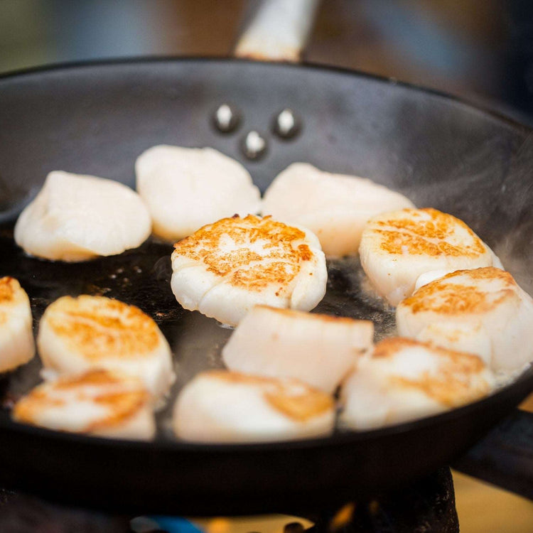 close up of scallops frying in cast iron pan