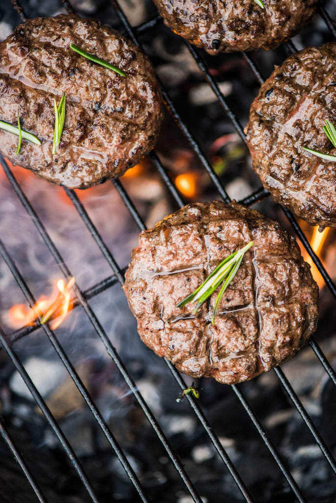 beef burgers on grill with flames