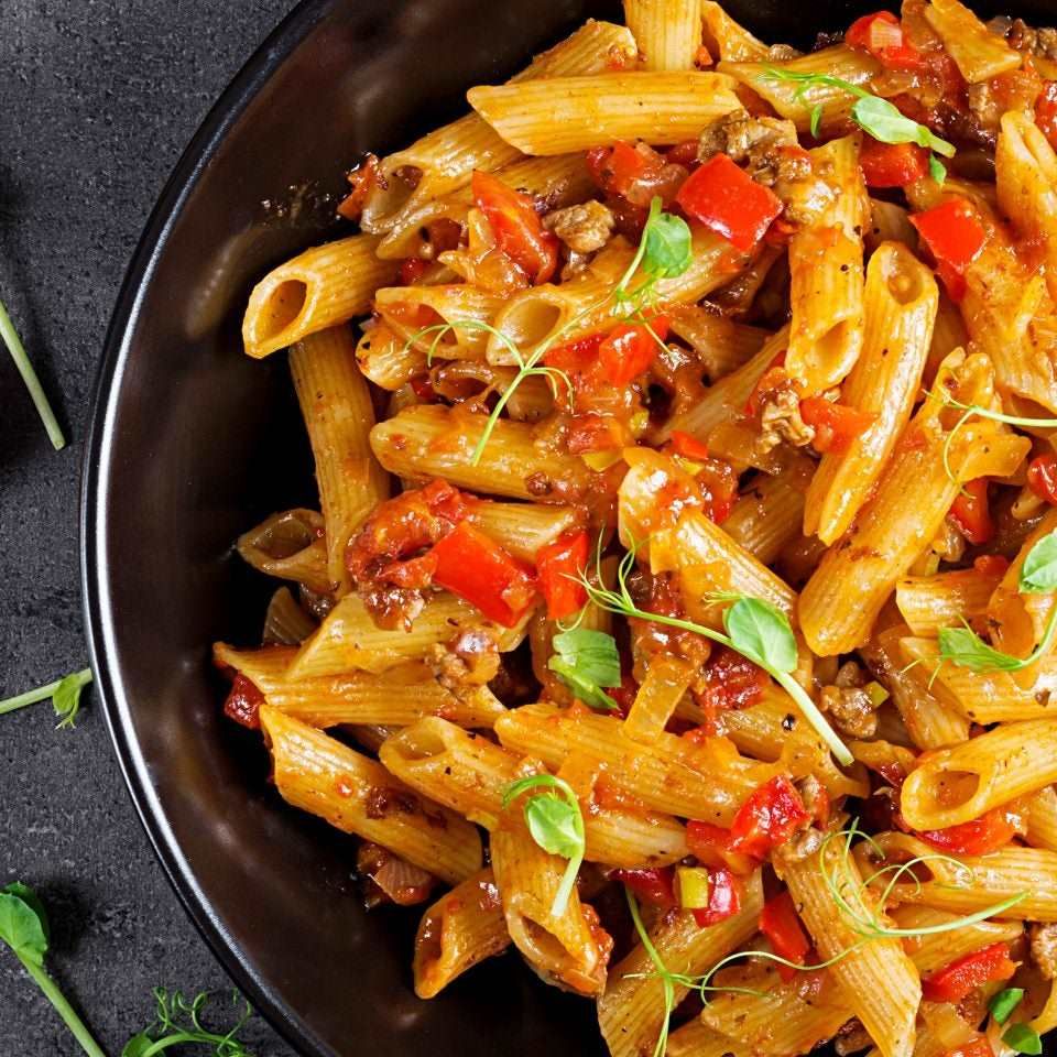 Penne pasta in tomato sauce with meat, tomatoes decorated with p