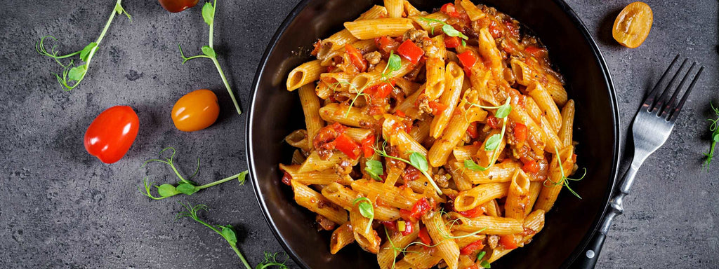 Penne pasta in tomato sauce with meat, tomatoes decorated with p