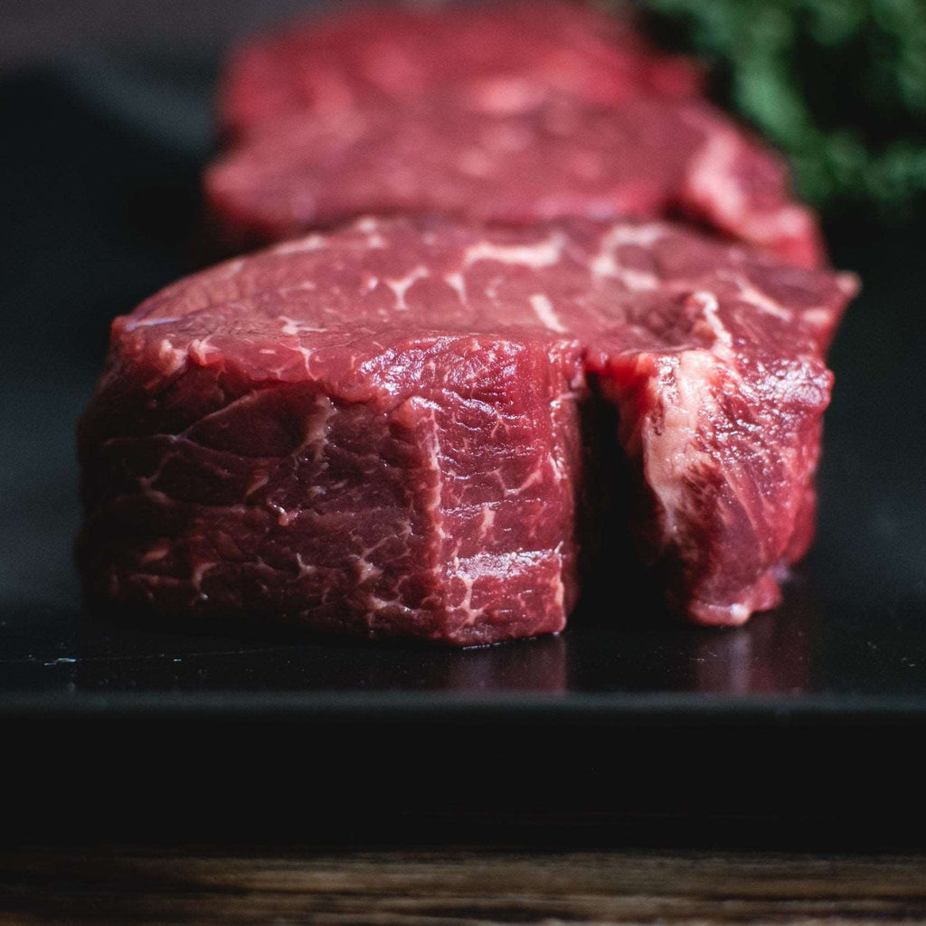 Raw beef steaks on a black plate