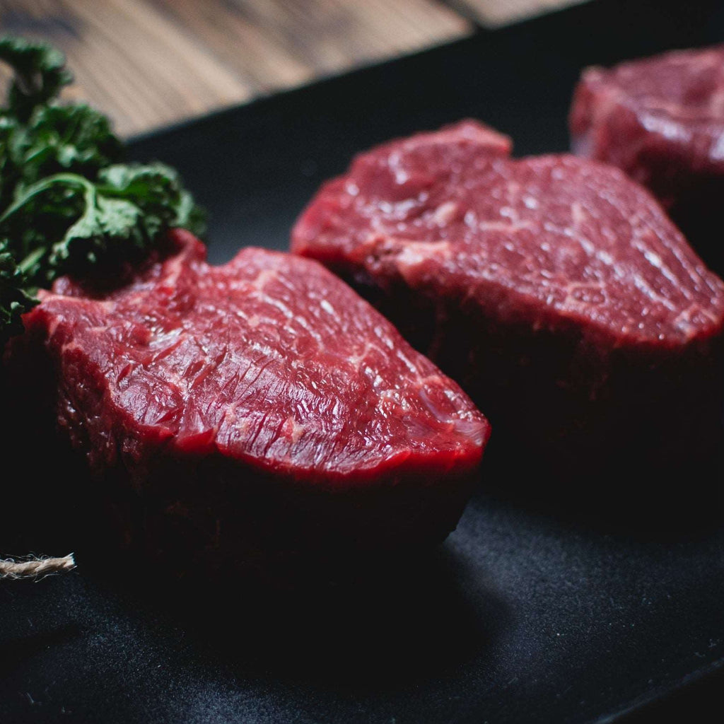 Raw beef steaks on a black plate