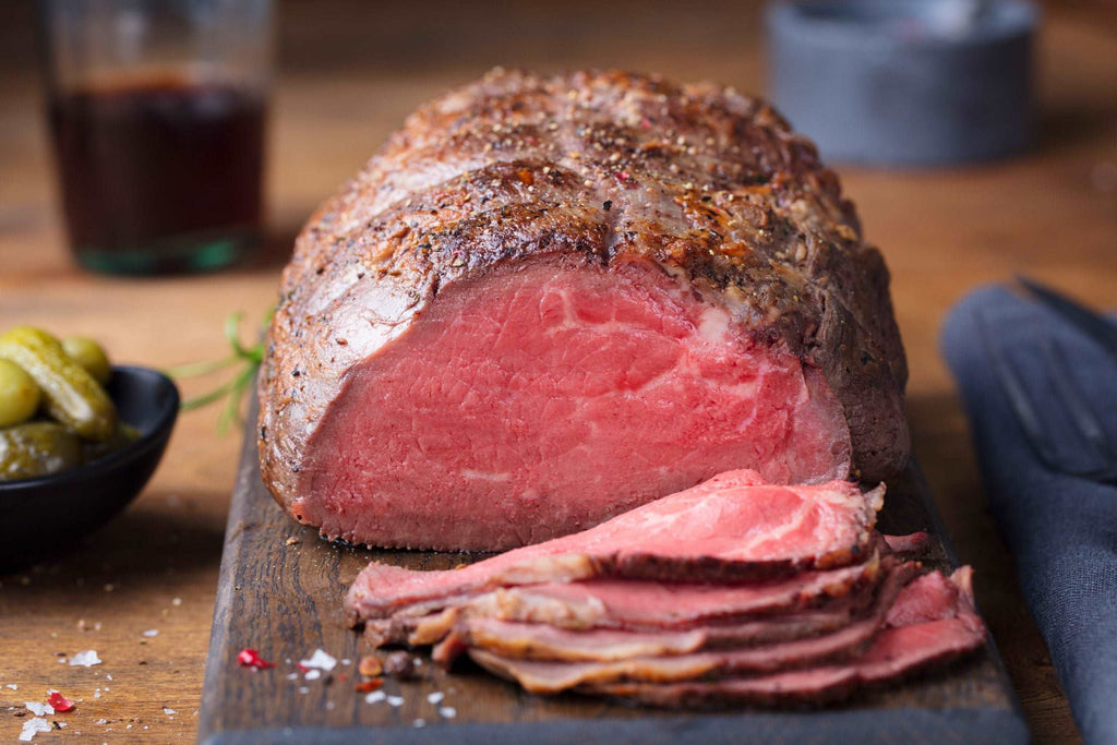 Roast beef on cutting board. Wooden background.